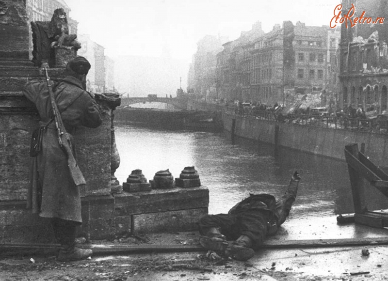 Берлин - Советский солдат осматривает местность на мосту реки Шпрее в Берлине. Рядом предположительно лежит труп советского танкиста.