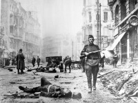 Берлин - Советский солдат идет мимо убитого гауптштурмффюрера СС в Берлине на перекрестке Шоссештрассе и Ораниенбургерштрассе.