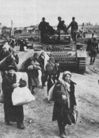 Волгоград - Советские беженцы идут по дороге мимо немецкого танка на подступах к Сталинграду. 1942 год.